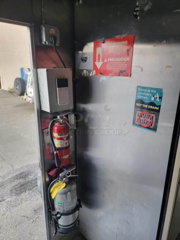 Fully equipped 24' Quality food trailer interior with stainless steel construction, fire extinguishers, and safety signs visible.