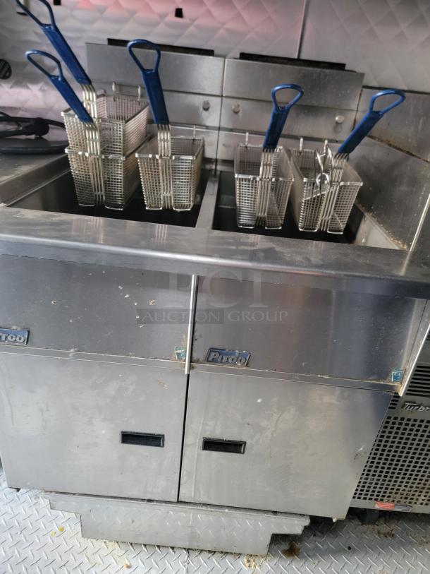 24' Quality food trailer interior with stainless steel fryers, baskets, and Turbo Air refrigeration, ready for high-volume use.