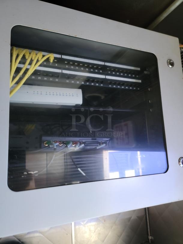 Network panel with Ethernet cables and switches inside a storage compartment of the Quality 24' food trailer.