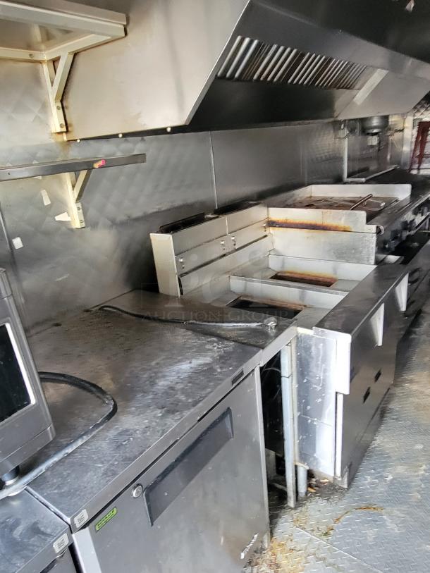 2020 24' Quality Food Trailer interior, featuring stainless steel kitchen equipment, vent hood, and storage space. Ready-to-use condition.