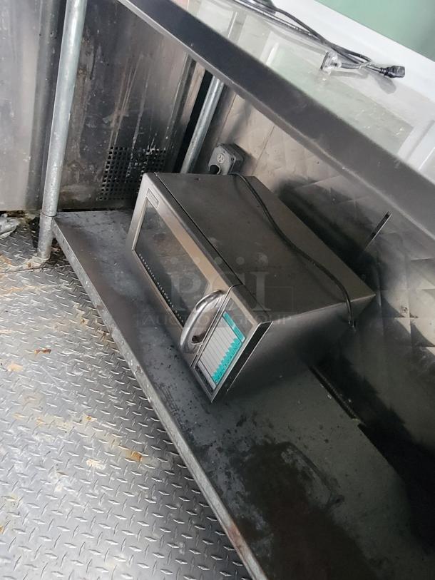 Inside view of a 2020 Quality 24' food trailer, featuring a stainless steel counter and a microwave. Ready for immediate use.
