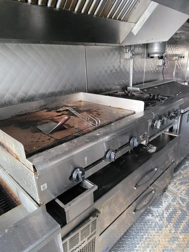 2020 24' Quality food trailer interior with grill, stovetop, and ventilation. Well-maintained, ready for business use.
