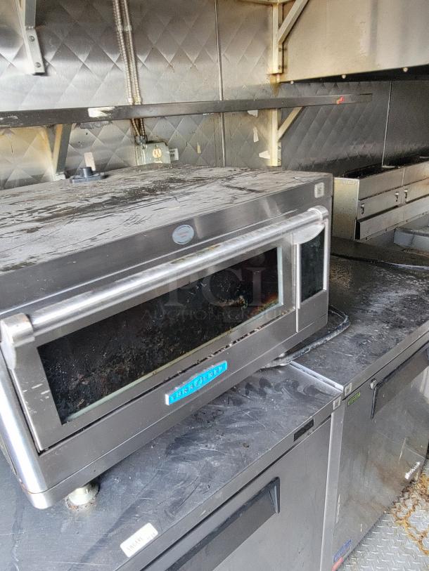 24' 2020 Quality Food Trailer interior, featuring a stainless steel oven and storage units. Well-maintained and fully equipped.