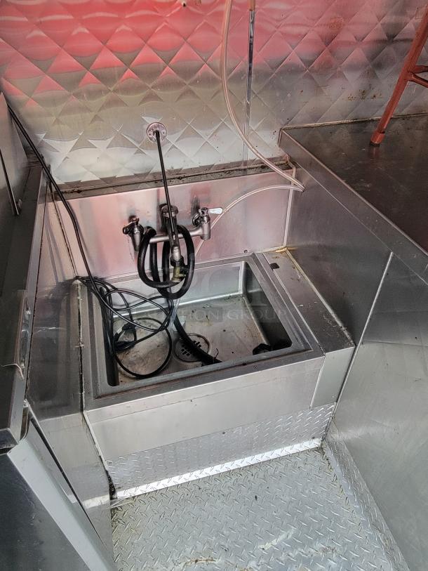 2020 Quality 24' food trailer interior, showcasing a stainless steel sink and backsplash, highlighting durability and cleanliness.