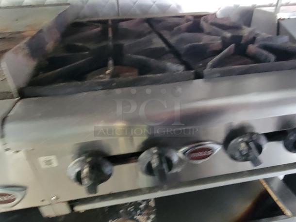 Stainless steel stove inside a 2020 24' Quality food trailer, featuring multiple burners and control knobs for precise cooking.