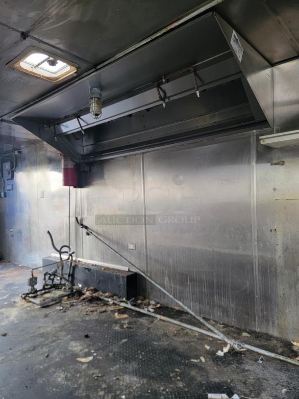 2019 Quality 24' food trailer interior, empty and ready for custom setup. Features ventilation hood, fair condition. Ideal for mobile food business.