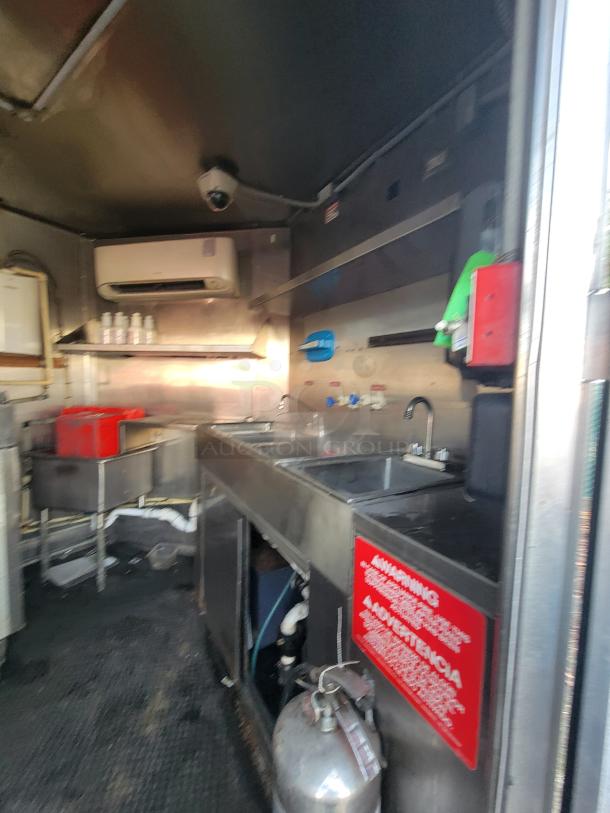 2019 Quality 24' food trailer interior with stainless steel sink, prep area, and appliances. Visible safety signage and equipment.