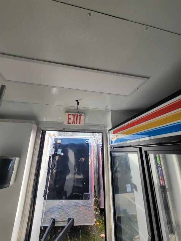 2021 SDG 20' mobile ghost kitchen trailer interior, featuring an exit sign, refrigeration unit with rainbow stripe accent.