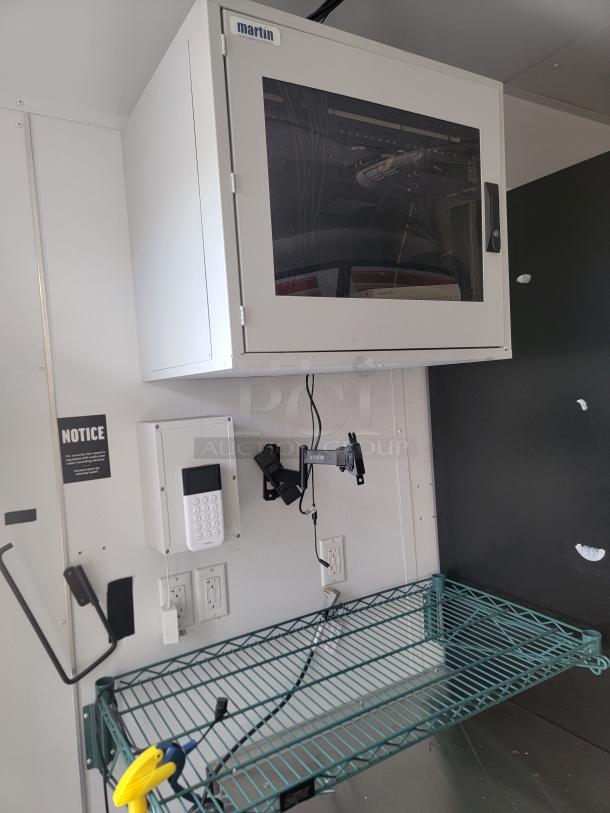 Interior of a 2021 SDG Ghost Food Trailer, showing electrical and shelving setup. Visible are a control panel and wiring.