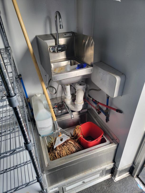 Stainless steel sink area in 2021 SDG Ghost Trailer, featuring plumbing fixtures, cleaning supplies, and Bosch water heater.