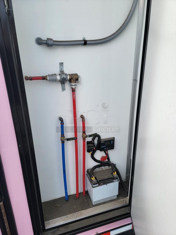 2021 SDG Ghost 20' food trailer plumbing and electrical panel, featuring red and blue pipes, battery, and control panel.
