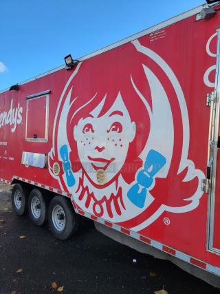 28' Rock Solid Cargo mobile kitchen trailer, bright red with Wendy's branding, three axles, ready for high-volume food service.