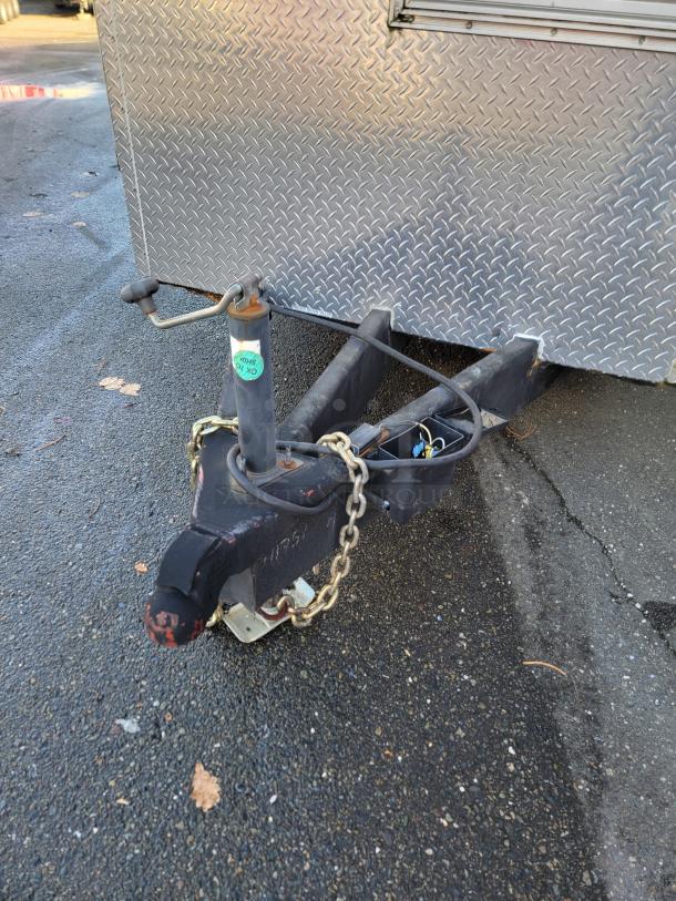 28' Rock Solid Cargo mobile kitchen trailer hitch and chains on asphalt, showcasing a durable diamond plate exterior.