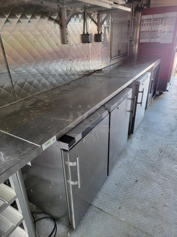 28' 2021 Rock Solid Cargo mobile kitchen trailer with stainless steel counters, commercial refrigeration, and diamond plate flooring.
