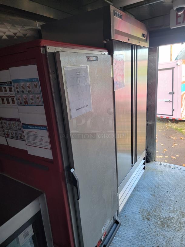 28' Rock Solid Cargo mobile kitchen trailer interior, featuring commercial refrigeration units and operational stickers, ready for high-volume food service.