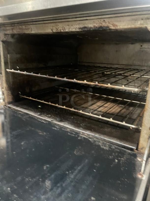 Vulcan 36SF-6BN commercial stove with 6 burners, convection oven, wired racks, backsplash, and salamander shelf, on casters.