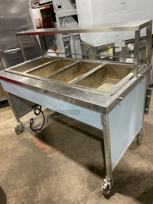 Atlas Metal 4-well stainless steel steamtable with sneeze guard and folding tray slide, Model WIH-D&M-4, on casters.