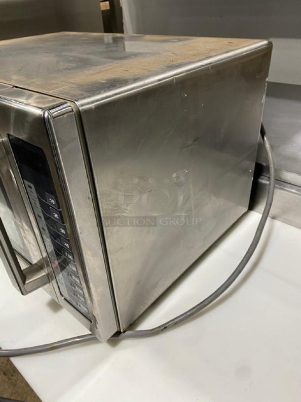 Amana 2021 stainless steel commercial microwave, model RCS10TS, with digital controls. Shows wear on top surface.