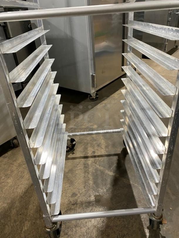 Commercial stainless steel pan holding/transport rack on casters, in used condition. Multiple slots for pans, durable design.
