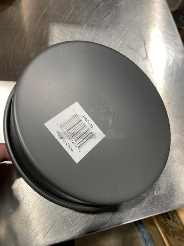 New Winco HAC-082 8"x2" anodized aluminum cake pan. Features durable construction. Label includes model and country of origin.