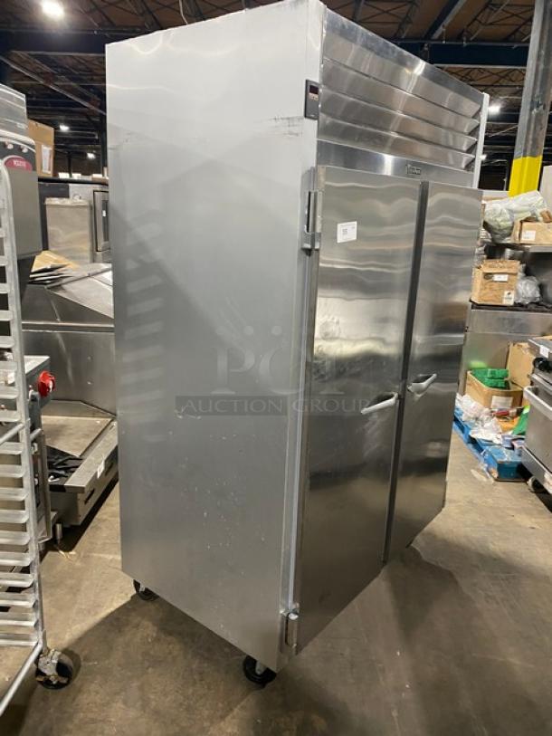 Traulsen model G22010 commercial stainless steel 2-door reach-in refrigerator with poly-coated racks, on casters.