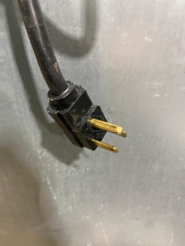 Black electric plug for the Traulsen G22010 refrigerator, showing three prongs.