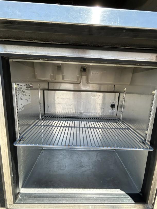 True TSSU-27-08 stainless steel 1-door sandwich prep table, open interior view, visible shelves, tags indicating model and specs.