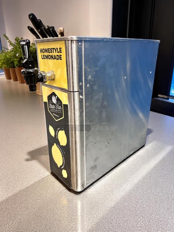 Newco FPM-1 stainless steel cold beverage dispenser, excellent condition, manual pour, "Homestyle Lemonade" label.