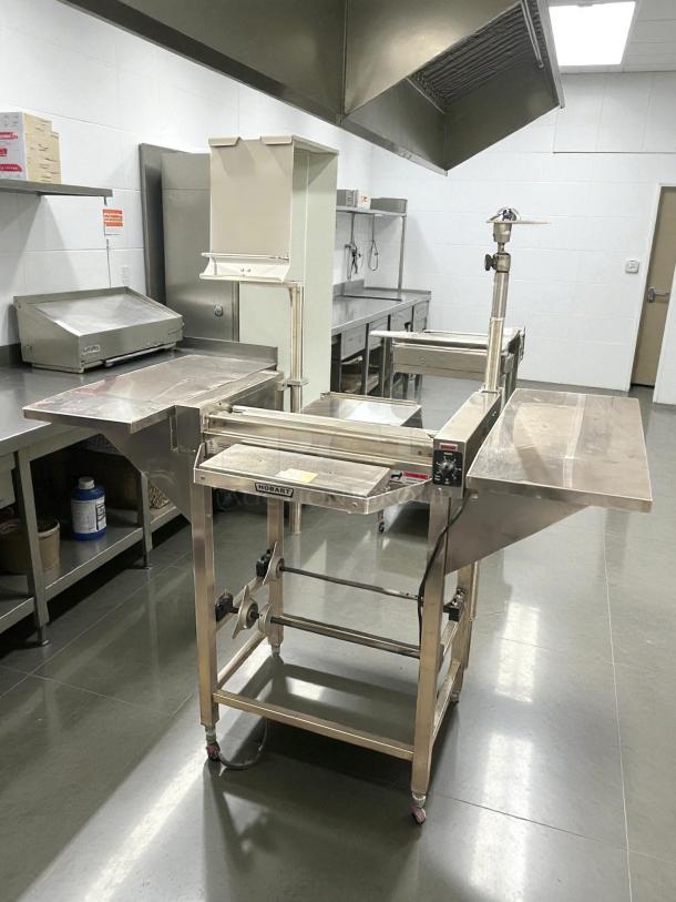 Hobart HWS-4-C floor model wrap station with built-in hotplate, two film roll capacity, in a commercial kitchen setting.