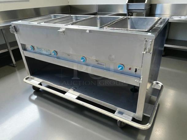 Duke E304 hot food table with 4 wells, cutting board, 58 3/8", tested, 240v/1ph. Stainless steel, excellent condition.