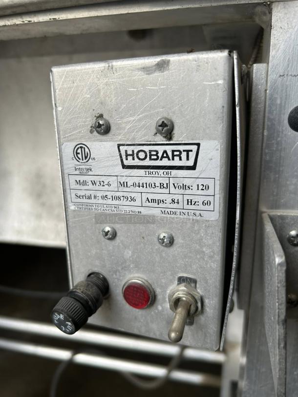 Hobart W32-6 hand wrap station, 120V, with 3 roll film capacity. Tested and working. Features control panel and power switch.