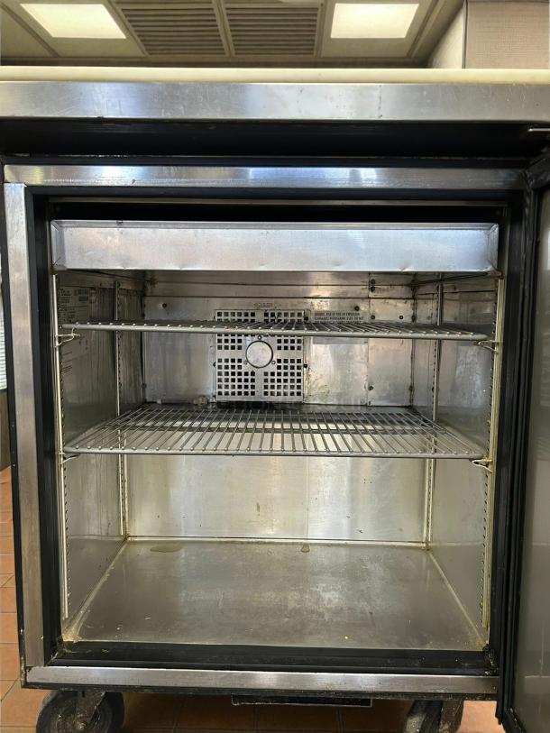 Alt text: True TSSU-27-08-HC 1-door sandwich/salad prep refrigerator, interior view, excellent condition, with shelves.