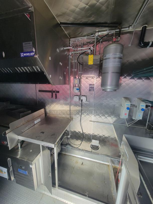 2021 16' Quality mobile food trailer interior with stainless steel walls, econ-air hood, electrical outlets, and fire suppression system.