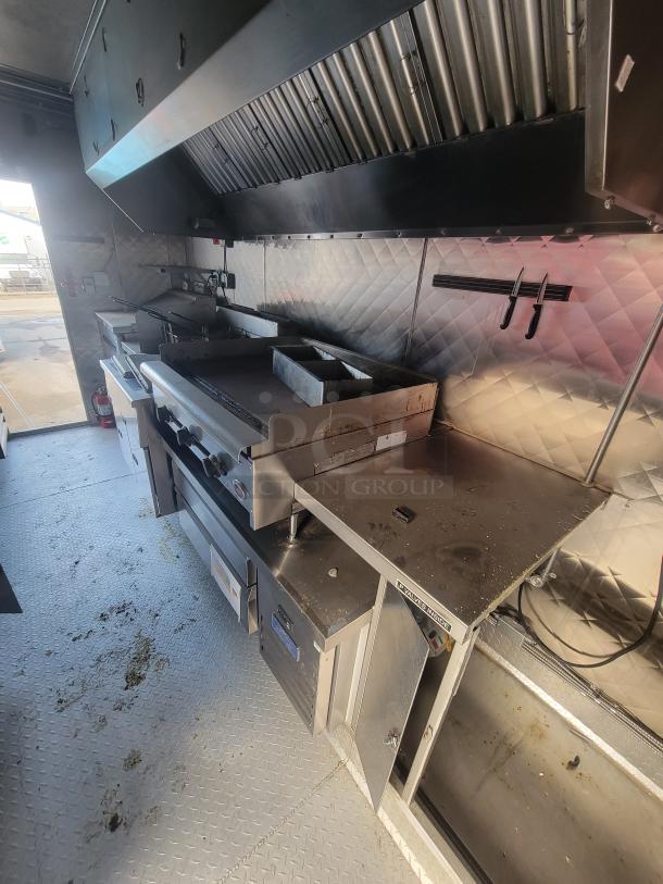 2021 16' mobile commercial ghost kitchen interior, featuring stainless steel surfaces, a large range hood, and commercial appliances.