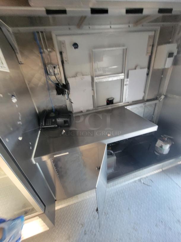 2021 16' Quality mobile ghost kitchen interior with stainless steel surfaces, counter, wiring, and storage.