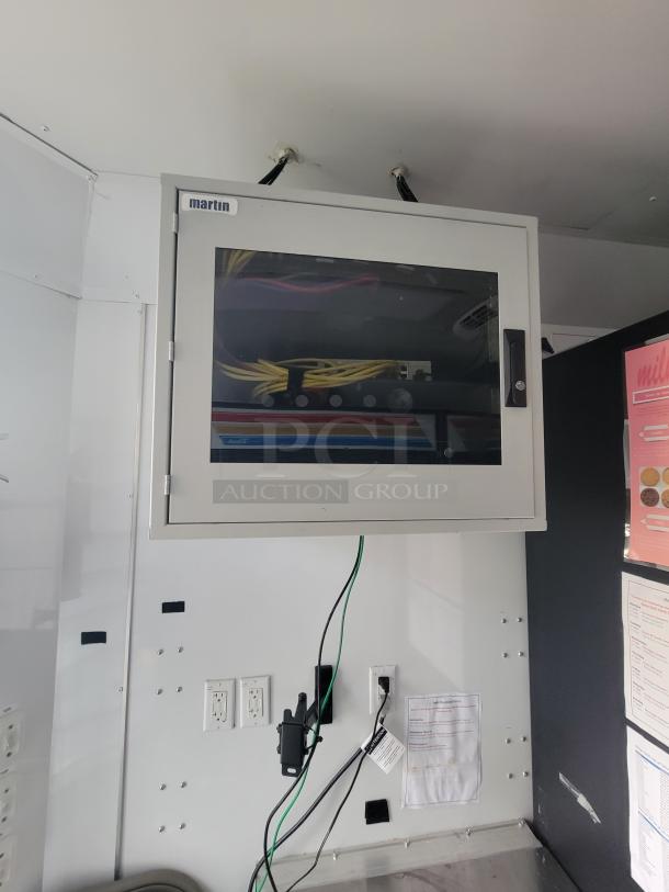 Martin electrical panel in SDG trailer interior with visible wiring. Includes outlets, mounted handset, and posted instructions.