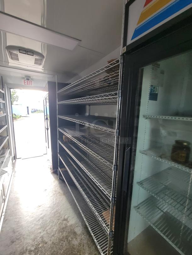 Interior of 2021 SDG 'Goodees' Retail/Food Trailer showing multi-tiered chrome wire shelving and part of a True Refrigeration unit.
