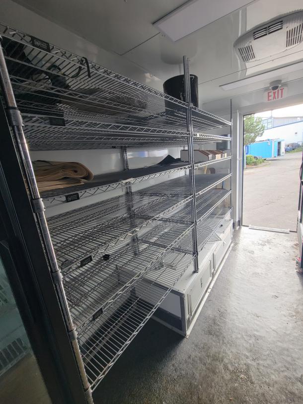 Interior of 2021 SDG "Goodees" Trailer showing multi-tiered chrome wire shelving and stainless steel countertop.