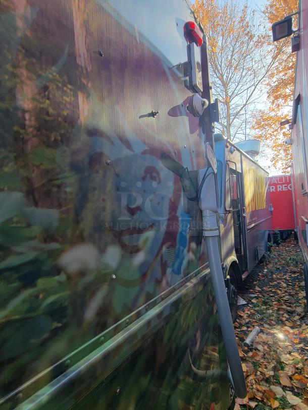 2004 Freightliner MT45 mobile kitchen exterior with custom graphic design, highlighting side panel and attached piping.