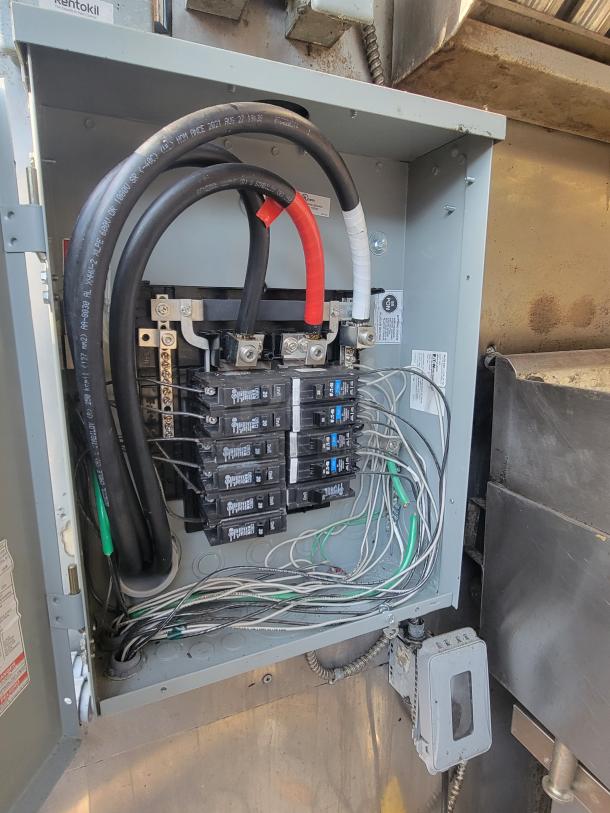 Electrical panel inside 2004 Freightliner MT45 mobile kitchen, showing wiring and circuit breakers for 240V/120V system.
