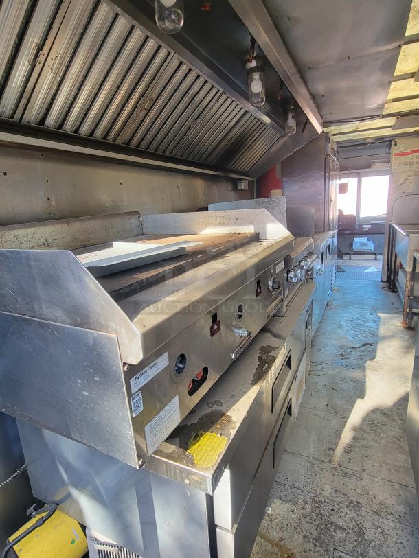 2004 Freightliner MT45 mobile kitchen interior with stainless steel cookline, Southbend griddle, exhaust hood, and fire system.