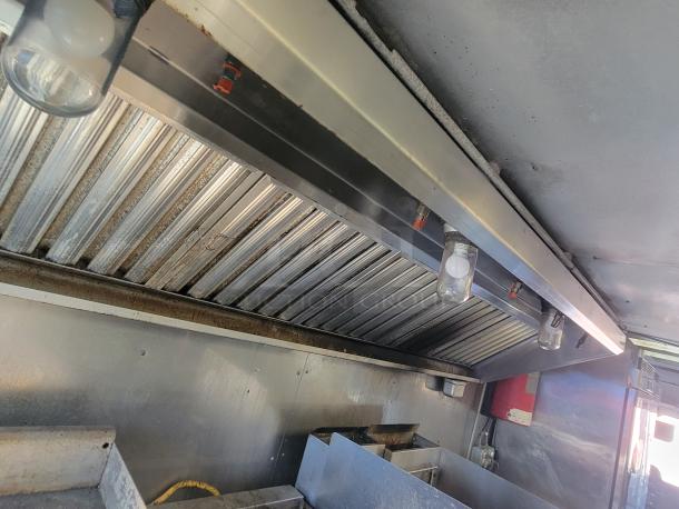 Interior view of 2004 Freightliner MT45 mobile kitchen showing stainless steel exhaust hood and integrated fire suppression system.