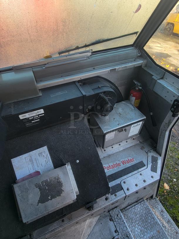 Interior view of a 2004 Freightliner MT45 mobile kitchen showing equipment space, fire extinguisher, and potable water label.