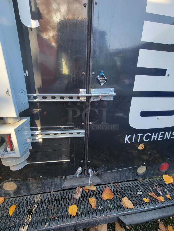 2004 Freightliner MT45 Step-Van rear view, black exterior, secure locks, visible electrical connections, scattered leaves.