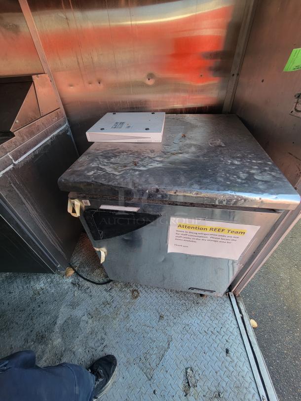 24' Mobile Ghost Kitchen trailer interior with stainless steel surfaces, a refrigeration unit, and a sign for Reef Team.