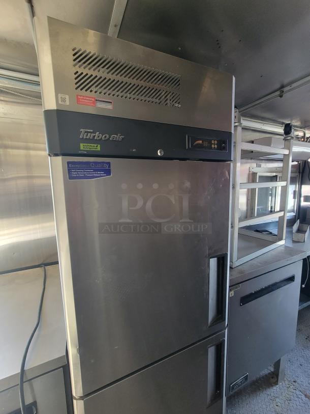 Turbo Air commercial refrigerator inside 2020 Diamond 24' mobile ghost kitchen trailer. Features stainless steel and energy-efficient hydrocarbon refrigeration units. Ideal for catering operations.