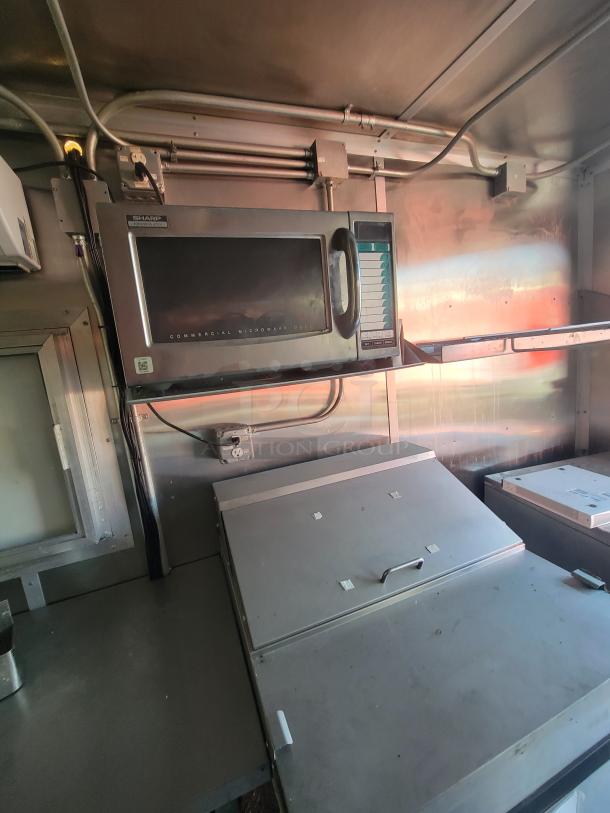 Diamond 24' mobile ghost kitchen trailer interior with stainless steel commercial-grade equipment, including microwave and refrigeration units.
