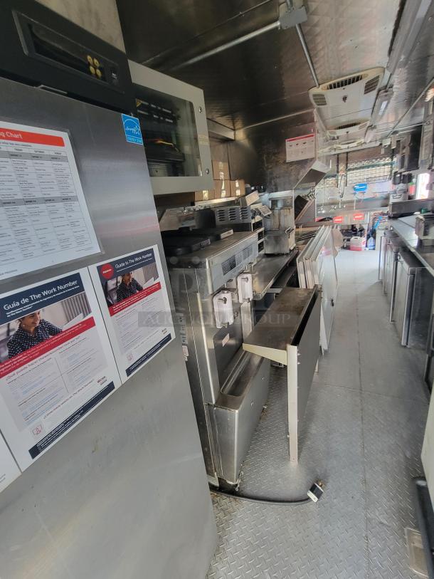 2022 Titanium 28' food trailer interior with high-end kitchen equipment, including Henny Penny fryer, commercial griddle, and Taylor soft serve machine, fully fitted for high-volume operation.