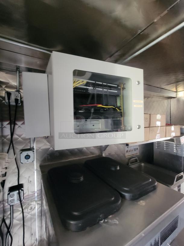 Interior of a 2022 Titanium Cargo 28' food trailer with commercial kitchen equipment, wiring, and storage units.