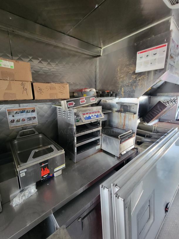 2022 Titanium Cargo 28' food trailer interior with commercial kitchen equipment, including a gas fryer and griddle.